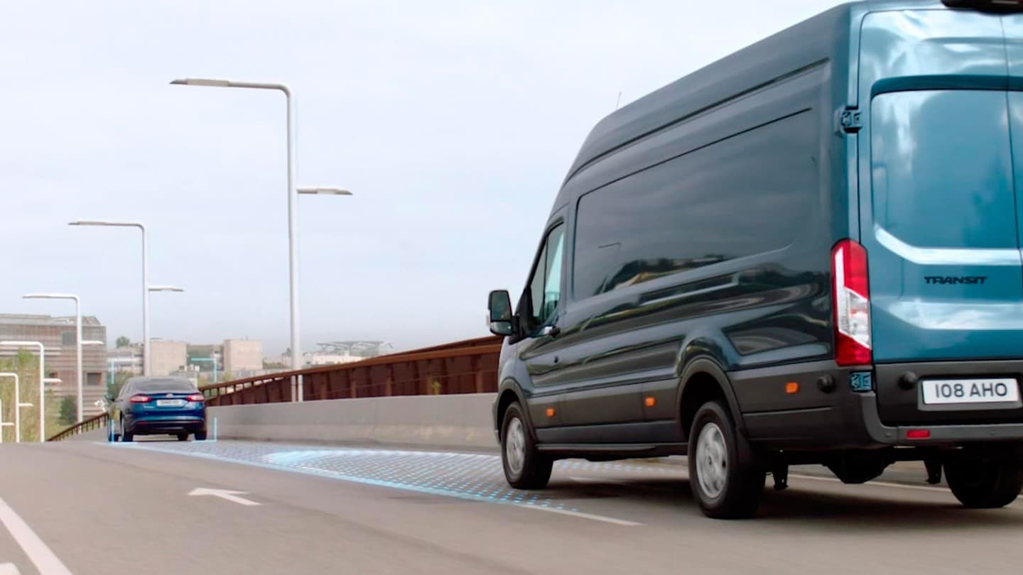 Side rear view of a new Ford Transit driving on a road